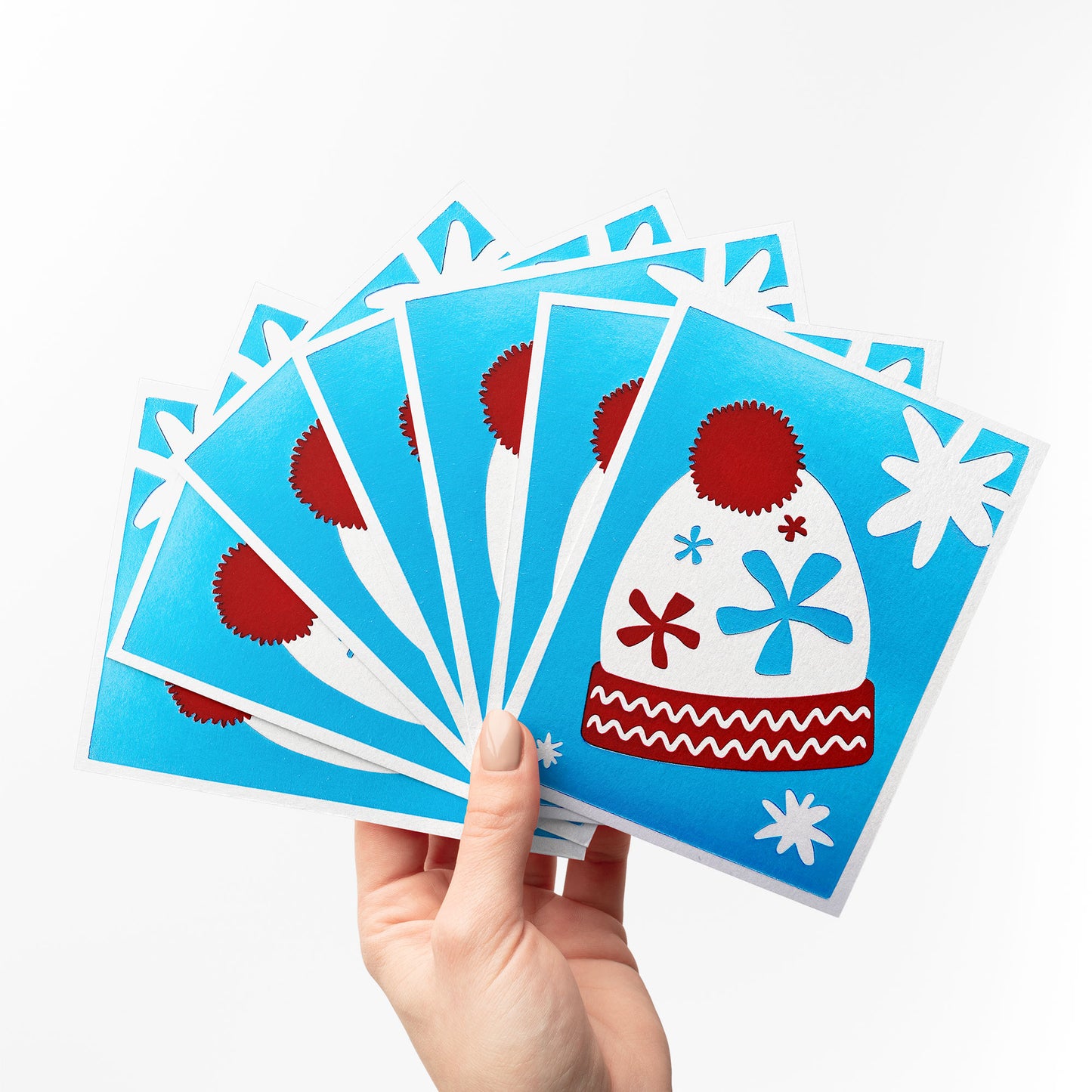 A fan-like arrangement of Twinkling Beanie Cards, showcasing the festive beanie design and snowflake details.